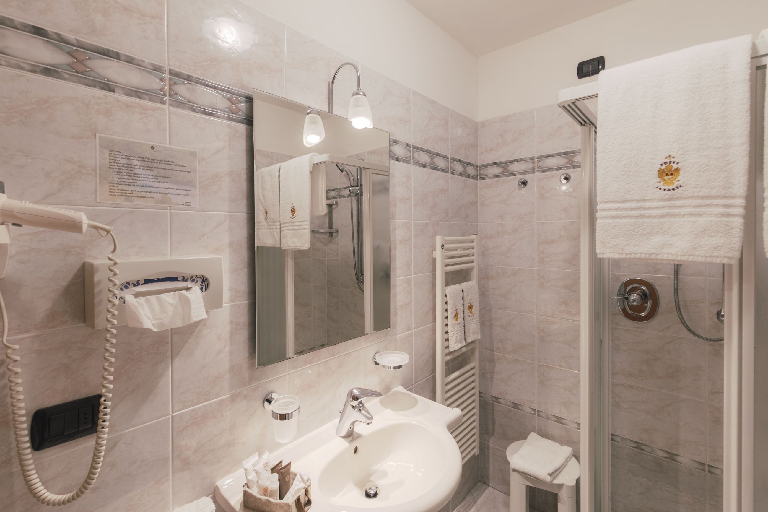 Ein Badezimmer mit Waschbecken, Spiegel, Handtuchhalter und Dusche.