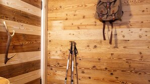 A wooden wall with a backpack, a pair of boots, and a tripod. - Hotel Astoria  (Primiero San Martino di Castrozza)