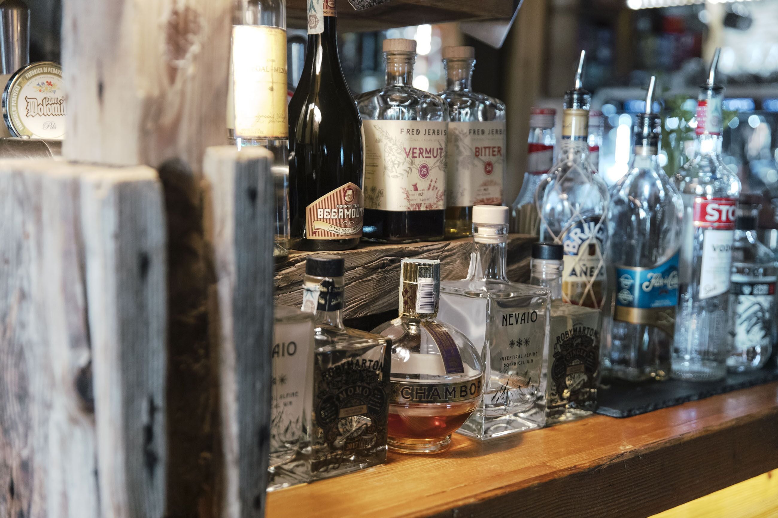 Un bar con varias botellas de licores, entre ellas vermut y champán.
