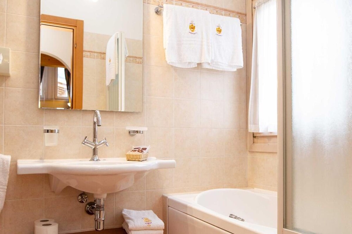 Un baño con lavamanos, espejo, toallero y bañera.