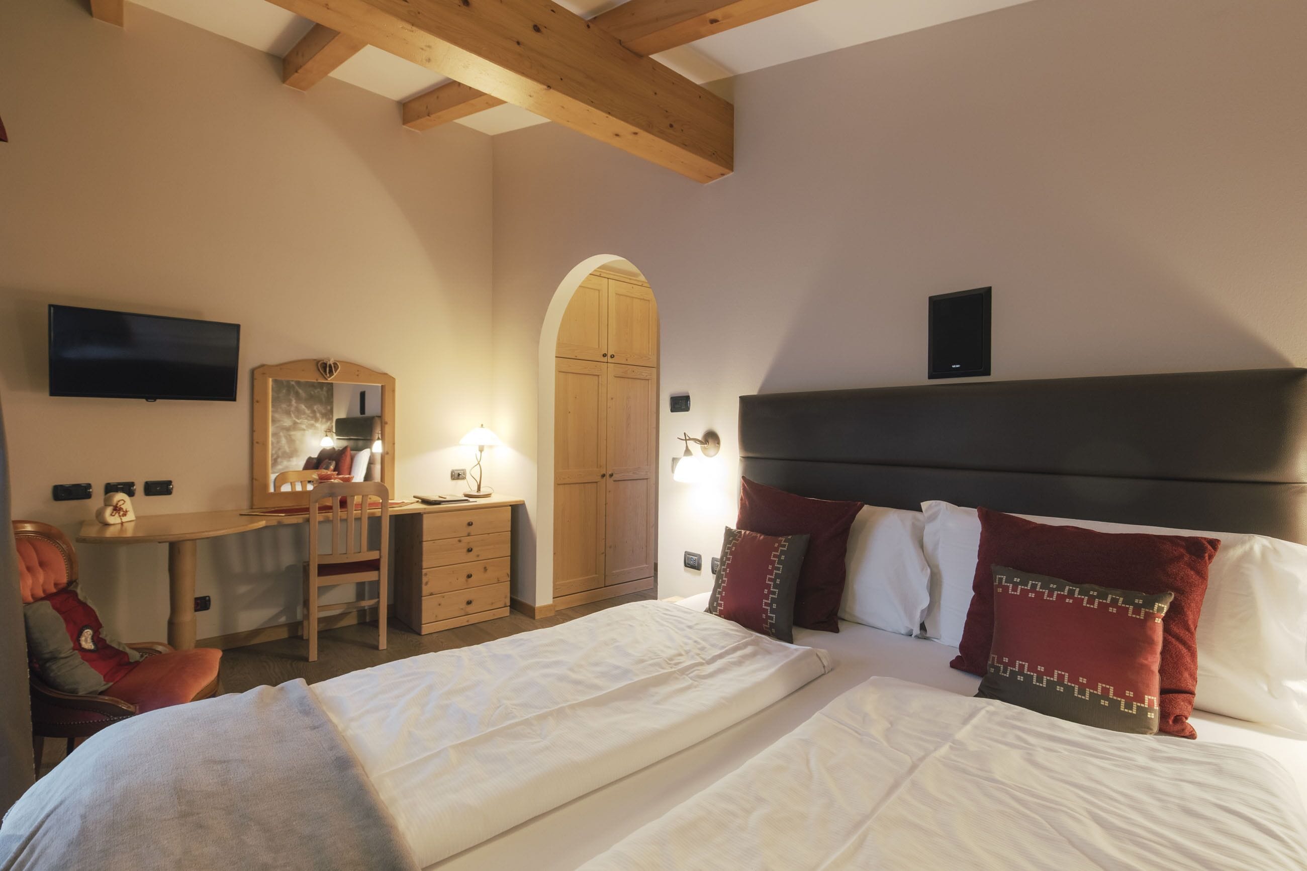 A bedroom with a bed, a desk, a chair, a TV, and a wardrobe.