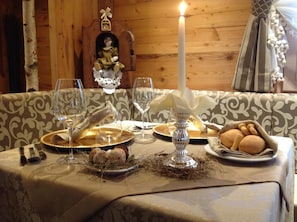 A dining table set with plates, glasses, and a candle, with a decorative figure and a candle holder in the background.