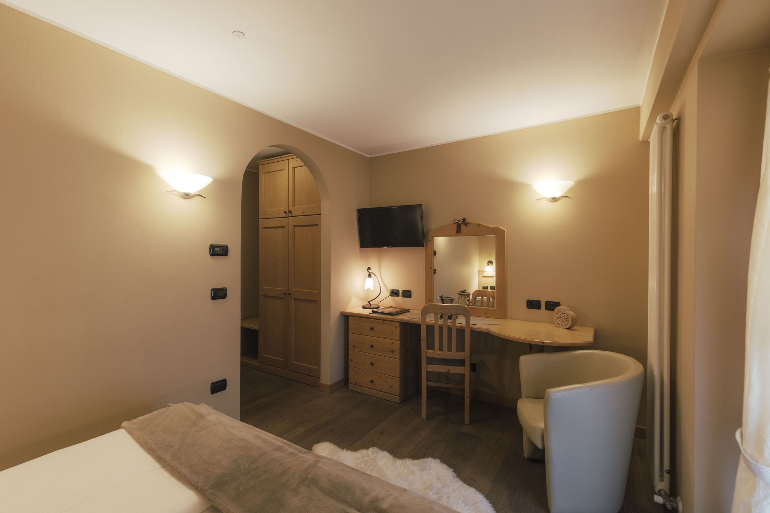 Une chambre à coucher comprenant un lit, un bureau, une chaise, une commode, un miroir et un téléviseur.