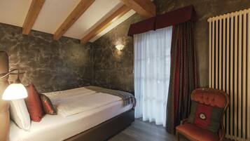A bedroom with a bed, a chair, a lamp, and a radiator.