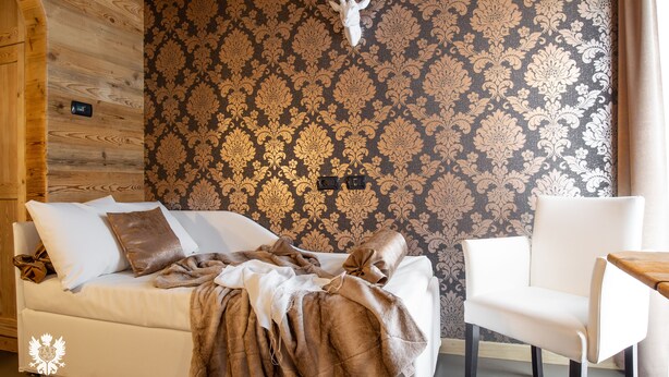 Um quarto aconchegante com uma cama, uma cadeira e um papel de parede estampado.