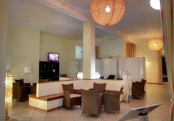 A hotel lobby with a reception desk, seating area, and a television. - Hotel Guardacosta (Diamante)