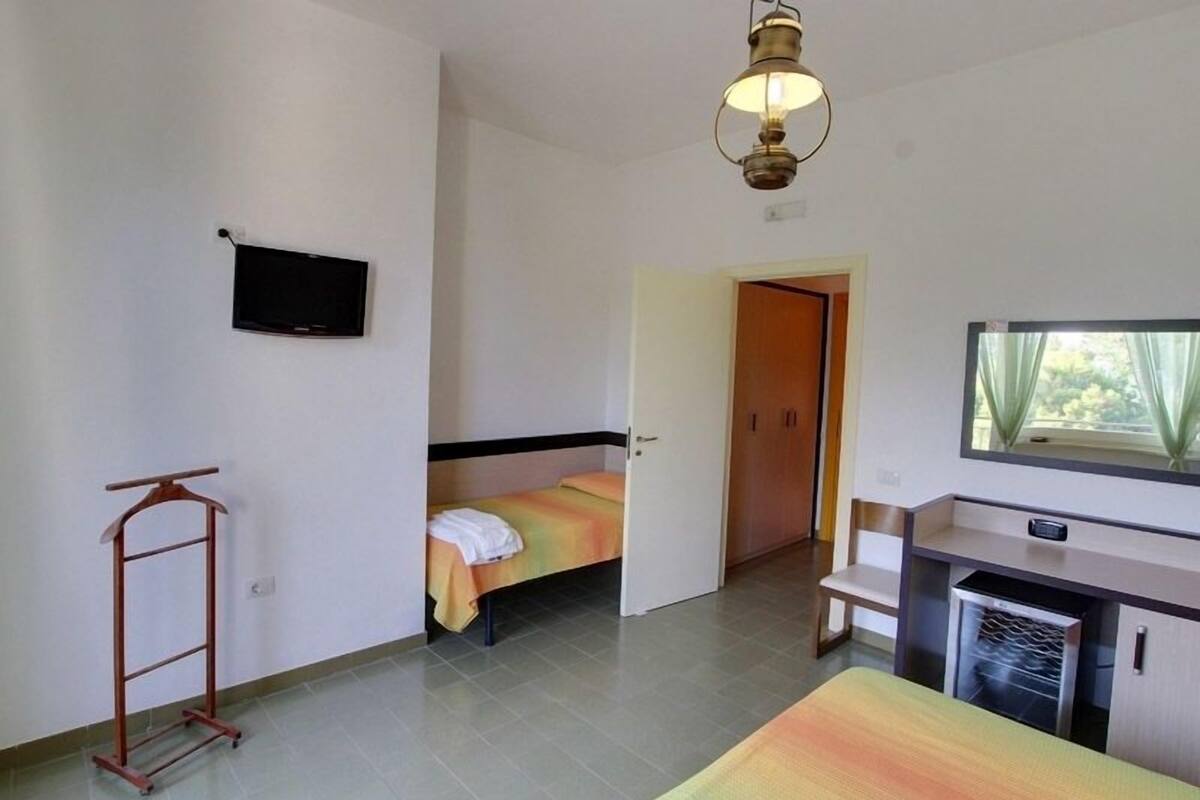 A compact room with a bed, a TV, a desk, and a wardrobe.