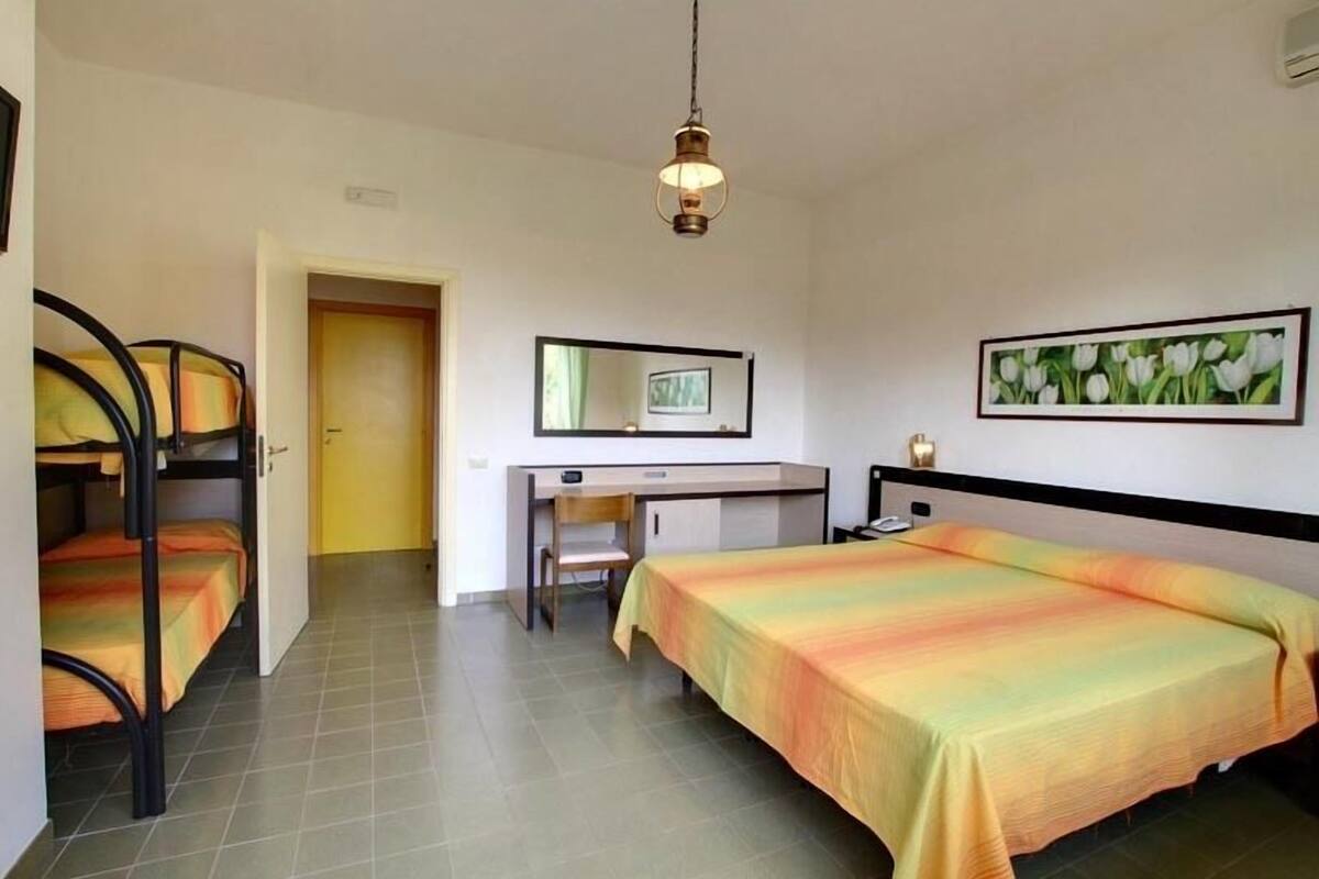 A bedroom with bunk beds, a desk, and a bed with a colorful blanket.