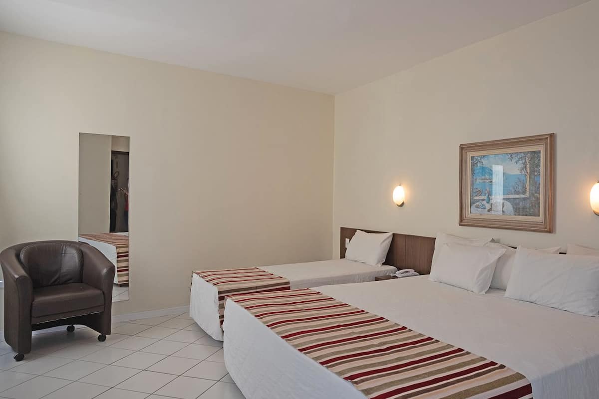 Een hotelkamer met twee bedden, een stoel en een schilderij aan de muur.
