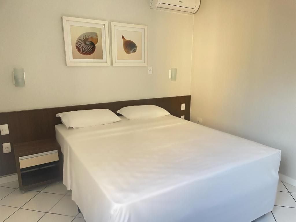 A neatly made bed with white linens in a hotel room.