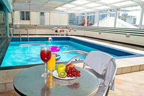 A poolside table with a drink, fruit, and a towel. - Atobá Praia Hotel (Balneário Camboriú)
