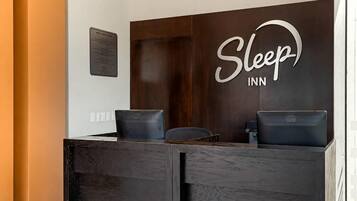 Una mesa de recepción con un letrero que dice 'Sleep INN', dos sillas negras y una computadora Dell.