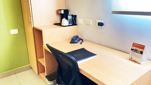 A small office space with a desk, chair, and a trash bin. There is a water bottle, a phone, and a coffee machine on the desk. - Sleep Inn Culiacan (Culiacán)