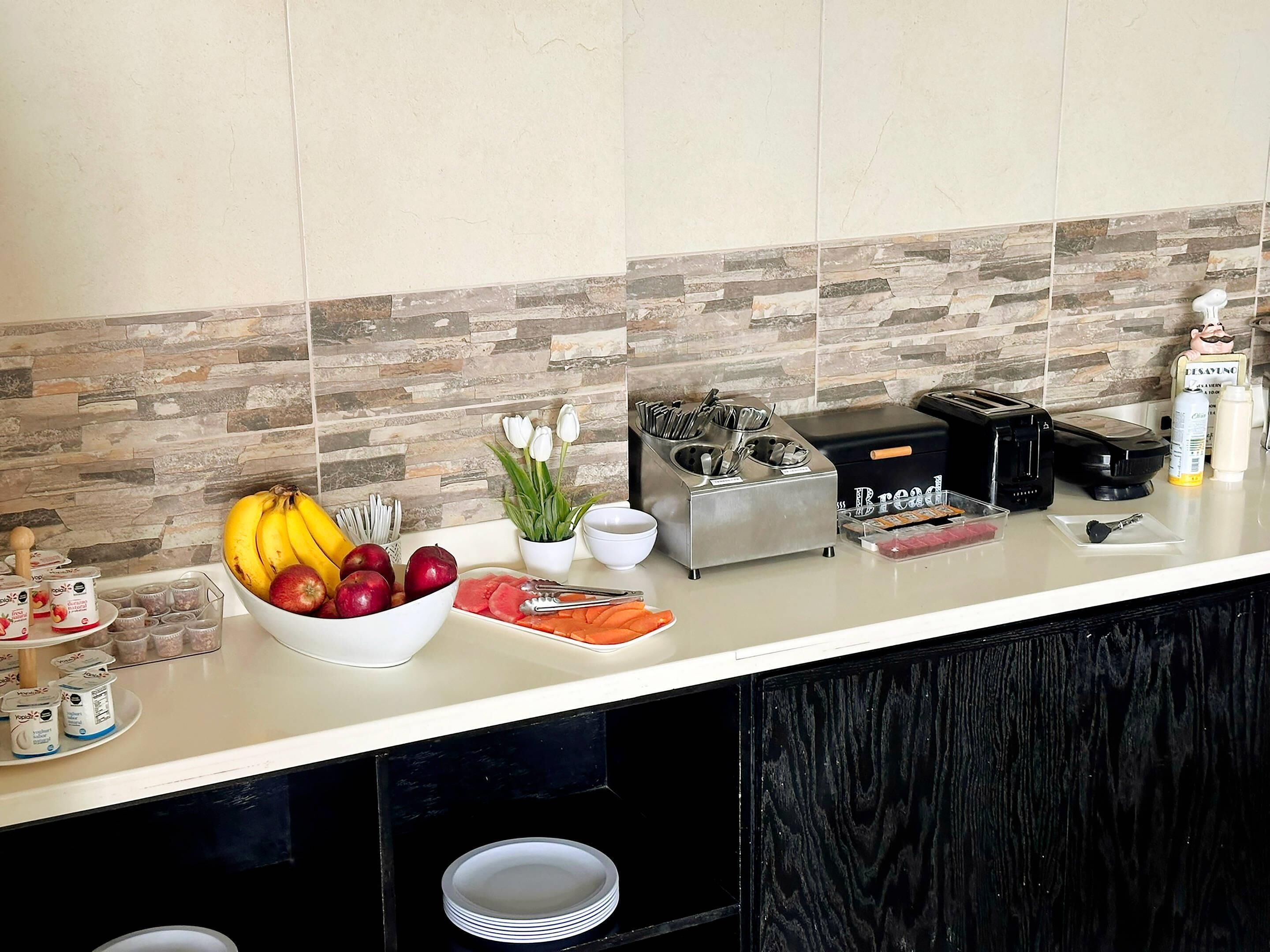 Una encimera de cocina con frutero, tostadora y varios electrodomésticos.