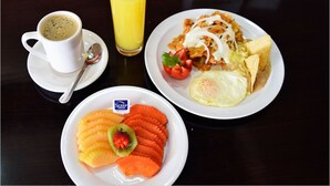 A breakfast plate with scrambled eggs, a fried egg, and a slice of toast, accompanied by a glass of orange juice and a cup of coffee. - Sleep Inn Culiacan (Culiacán)
