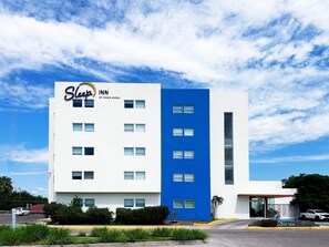 Un hotel Sleep Inn amb disseny modern, amb façana blava i blanca, nombroses finestres i una zona d'aparcament amb vorera groga.