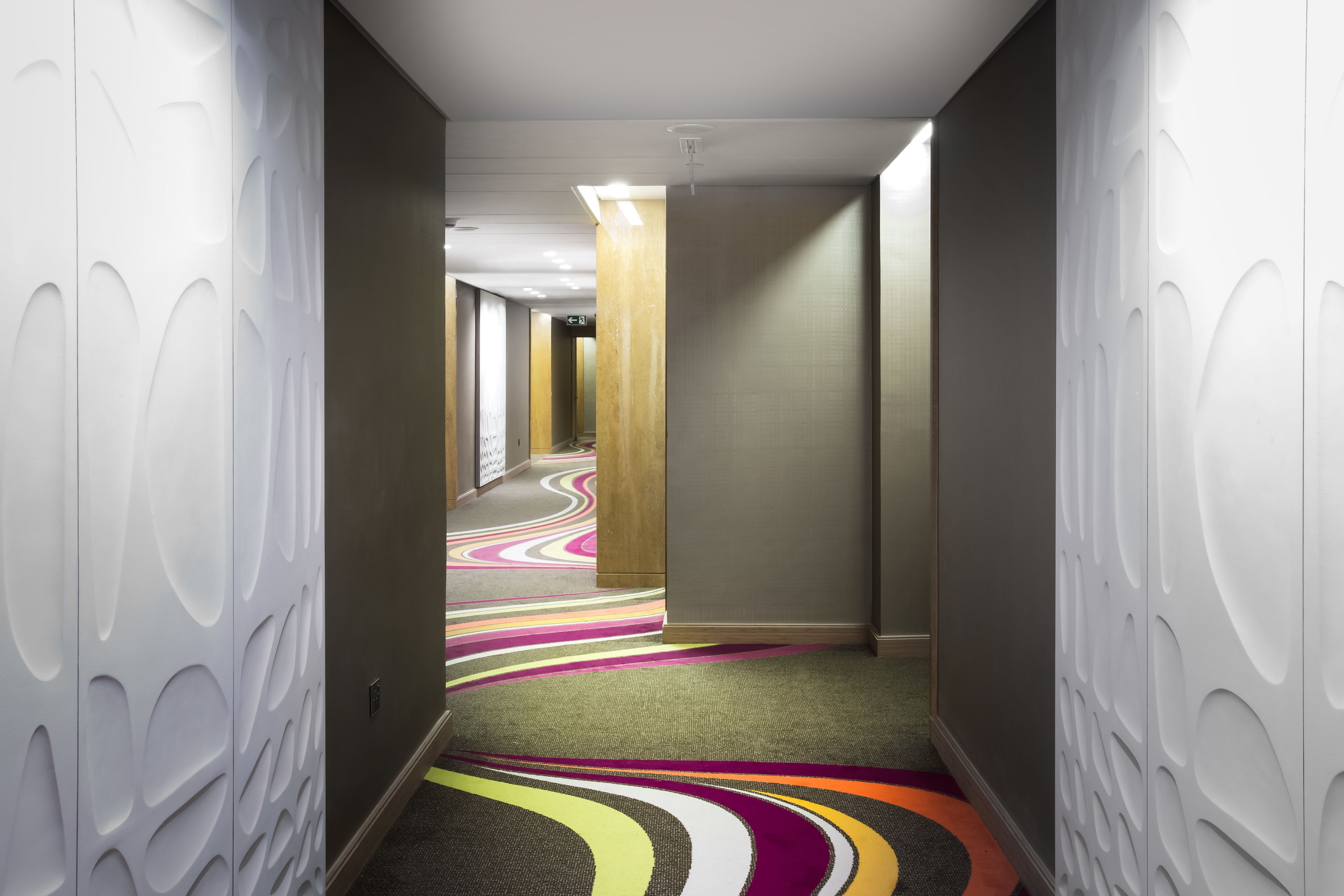 A hallway with patterned walls and a colorful carpet.