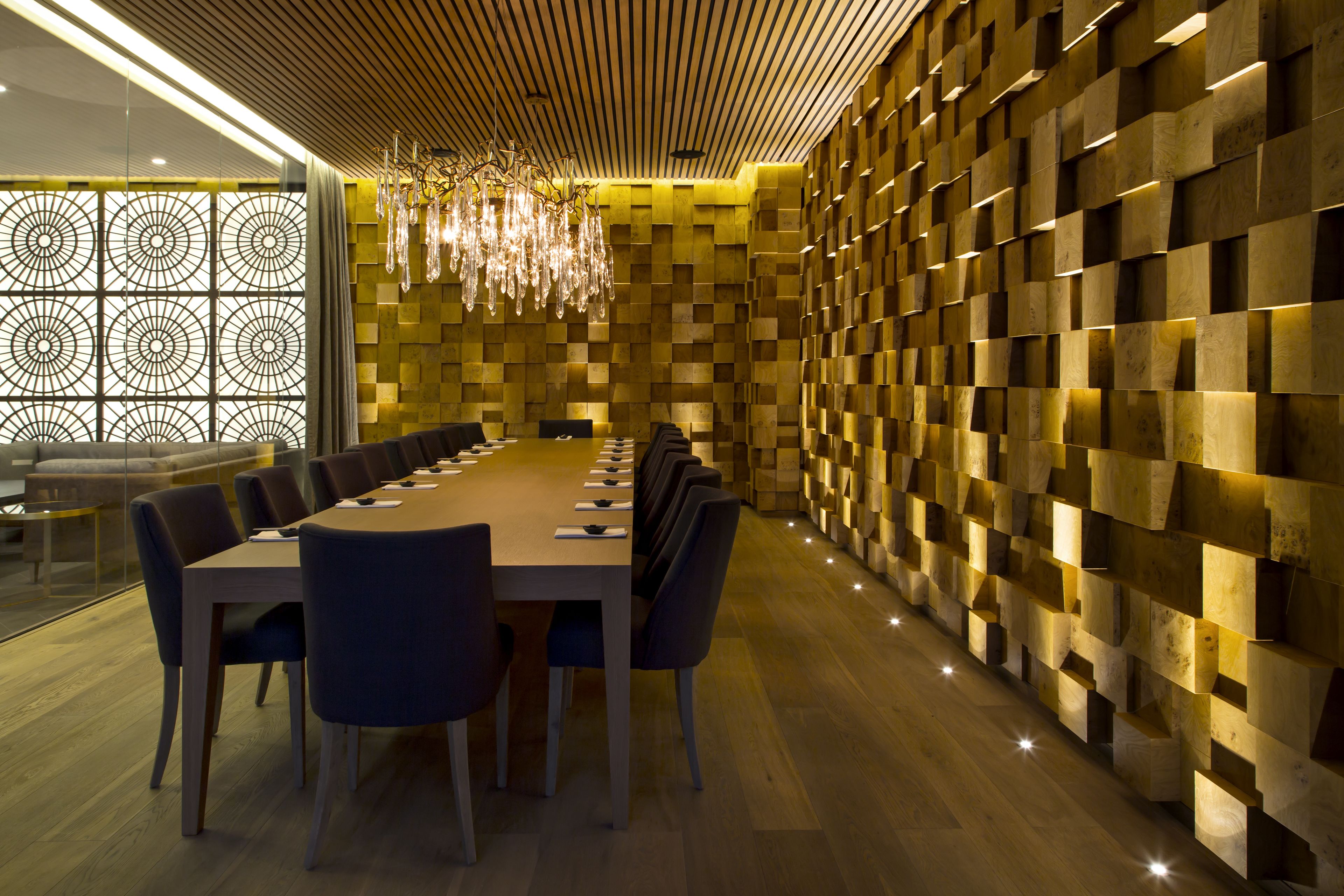 Een moderne vergaderzaal met een lange tafel, stoelen en een behang met een patroon.