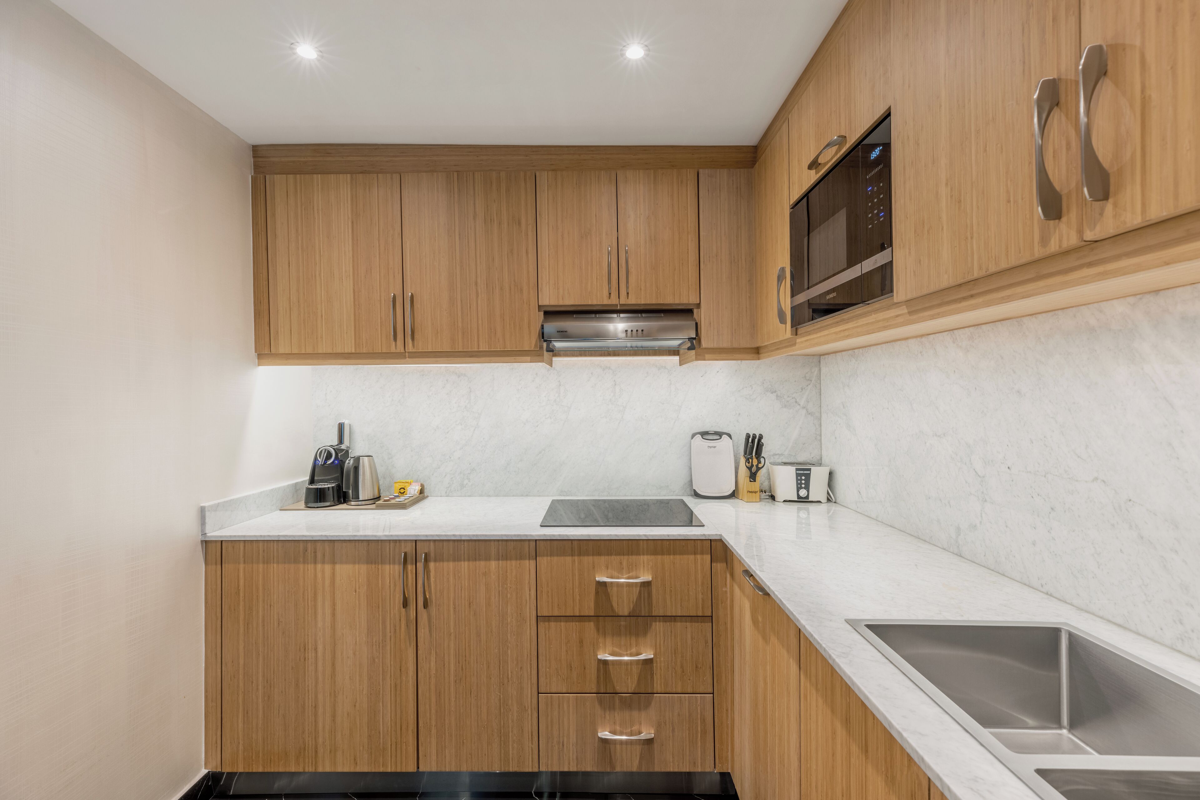 A modern kitchen with wooden cabinets, a stainless steel sink, and a built-in microwave.