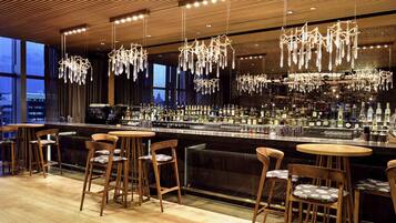 A modern bar with wooden furniture and hanging crystal chandeliers.