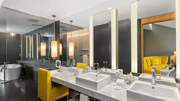 Une salle de bain moderne avec un grand miroir, deux lavabos, une baignoire et une chaise jaune.