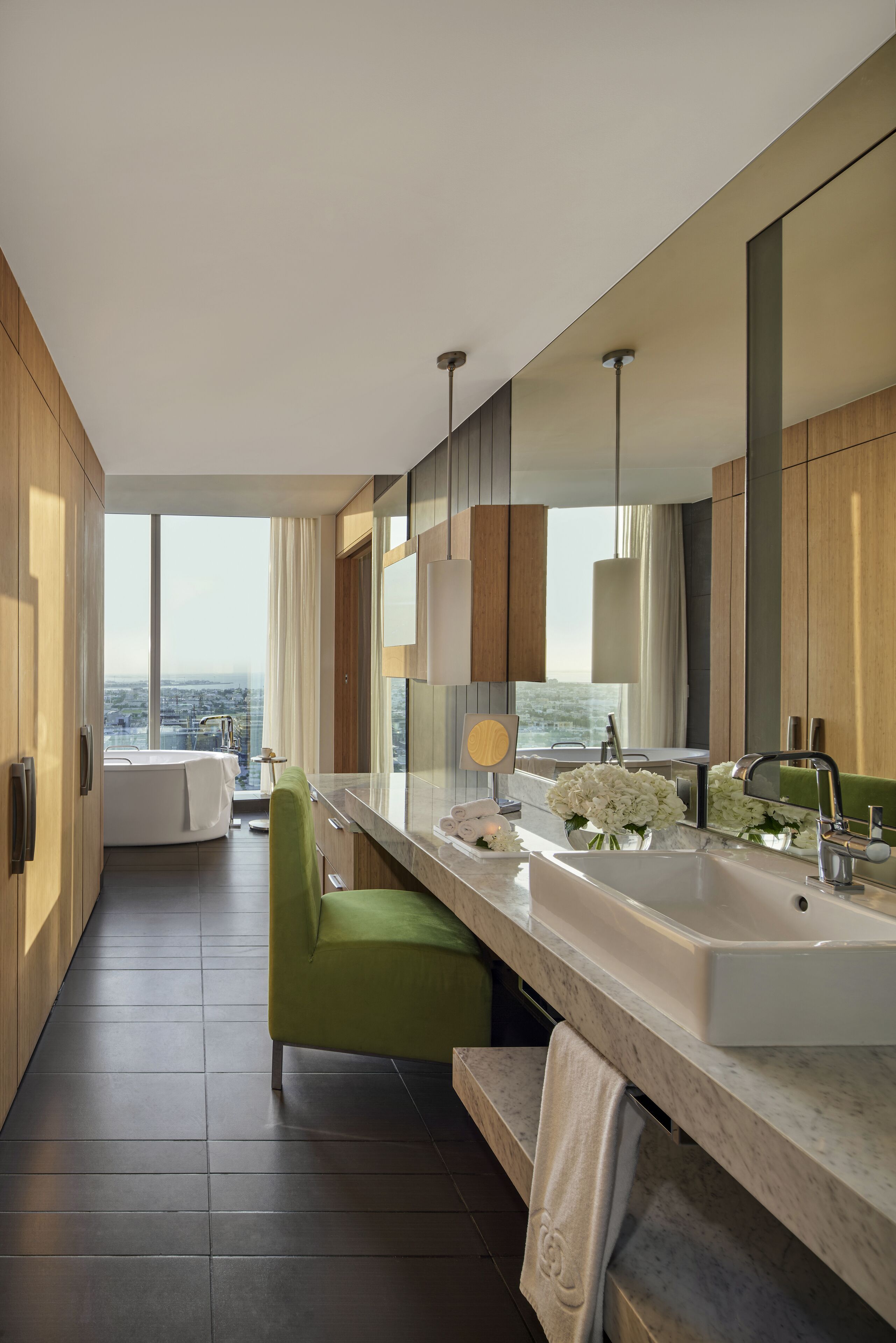 A modern bathroom with a large mirror, dual sinks, and a view of the city.