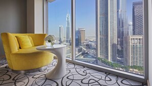 A modern room with a yellow armchair, a small white table, and a large window offering a cityscape view. - Sofitel Dubai Downtown (Dubai)