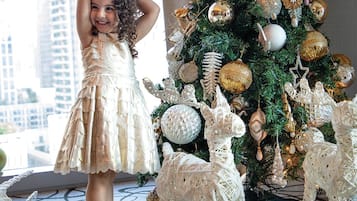 A child standing next to a Christmas tree with white and gold ornaments, surrounded by white reindeer figures.