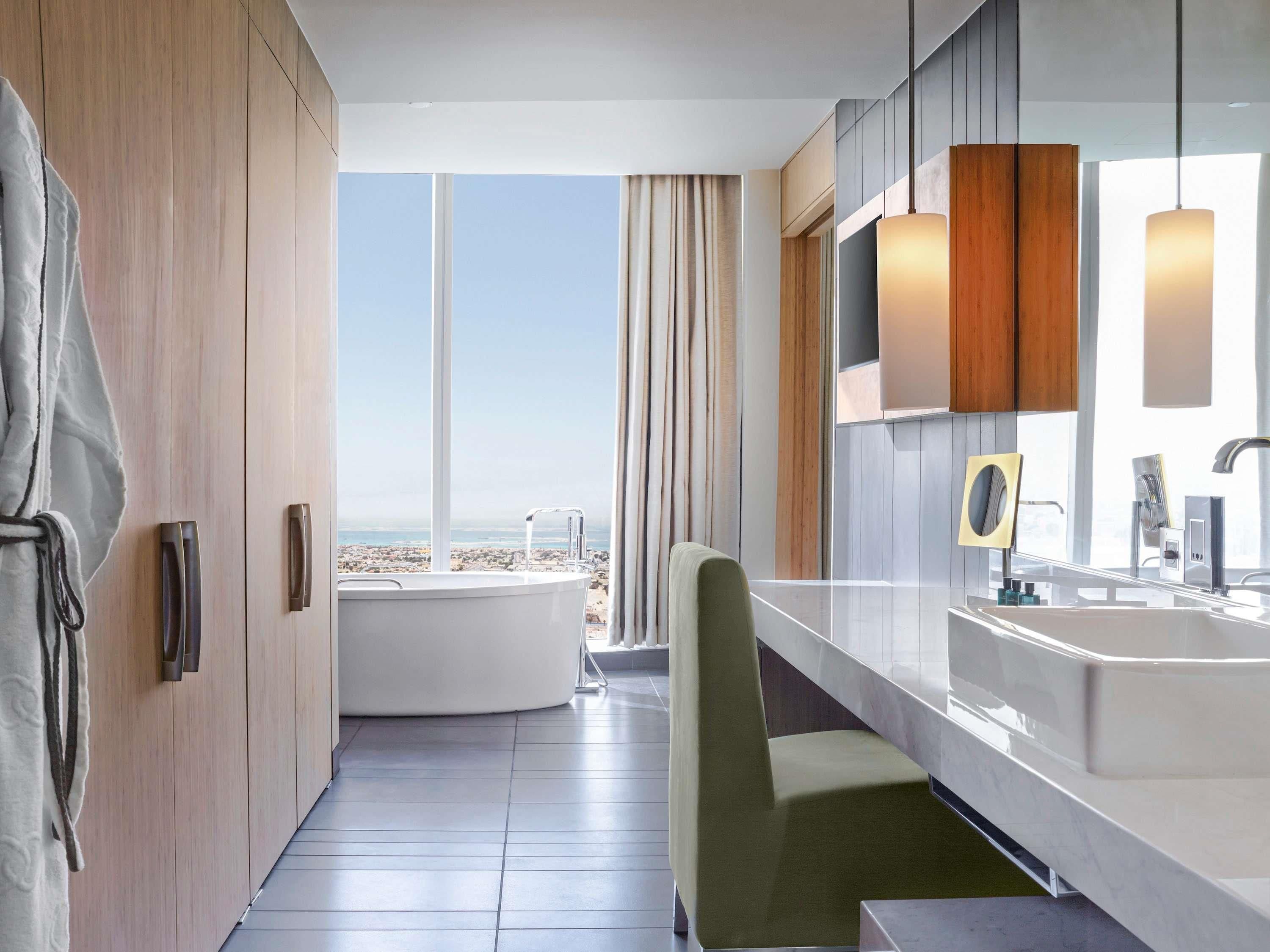 Ein modernes Badezimmer mit einer Badewanne, einem großen Spiegel und Blick auf den Strand.