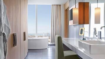 Ein modernes Badezimmer mit einer Badewanne, einem großen Spiegel und Blick auf den Strand.
