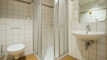 A bathroom with a toilet, a glass-enclosed shower, and a sink.