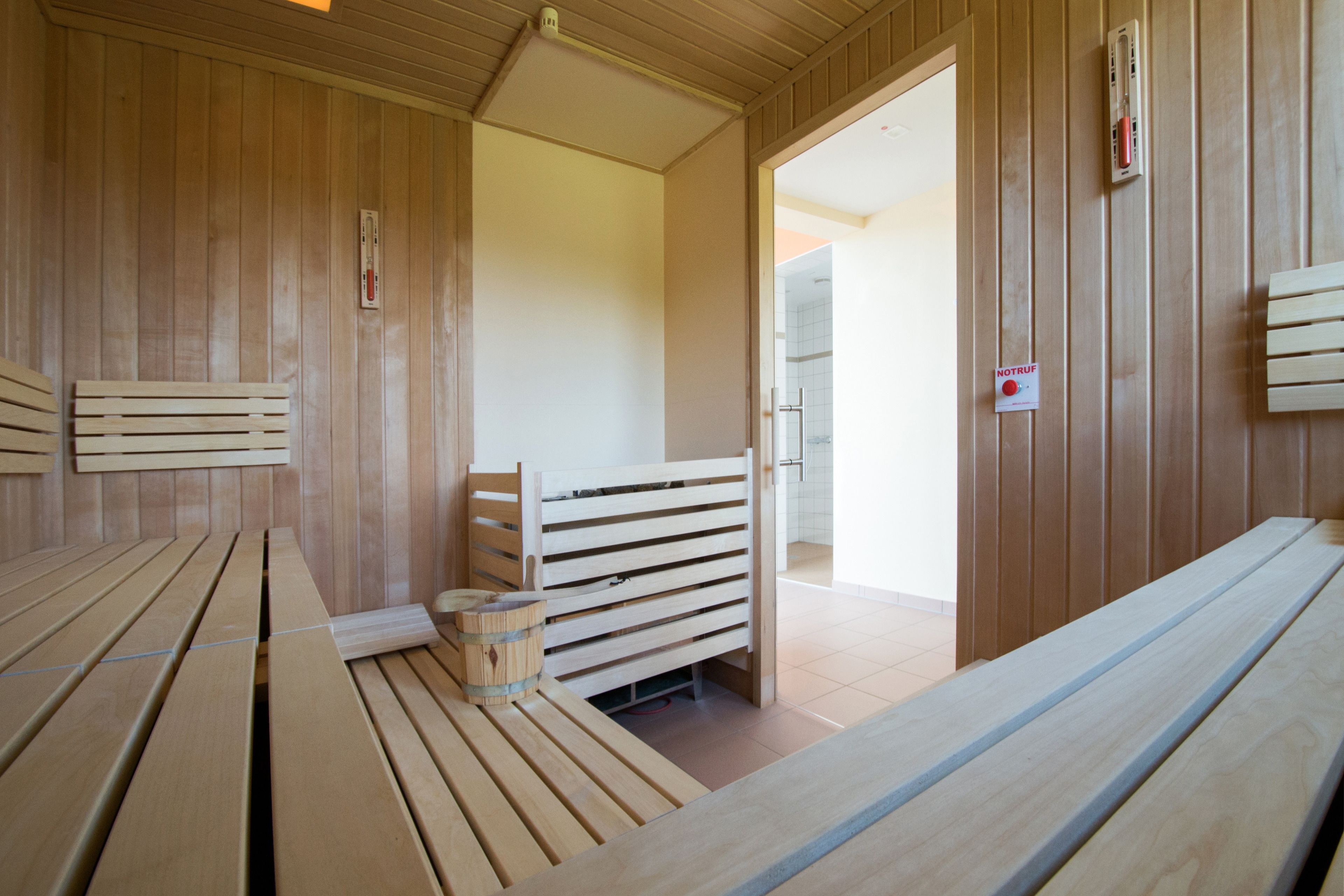 A sauna with wooden benches and a bench with a bucket.