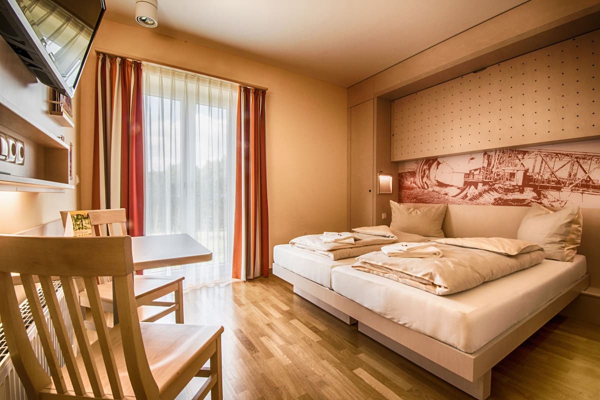 A hotel room with a bed, a desk, and a chair.