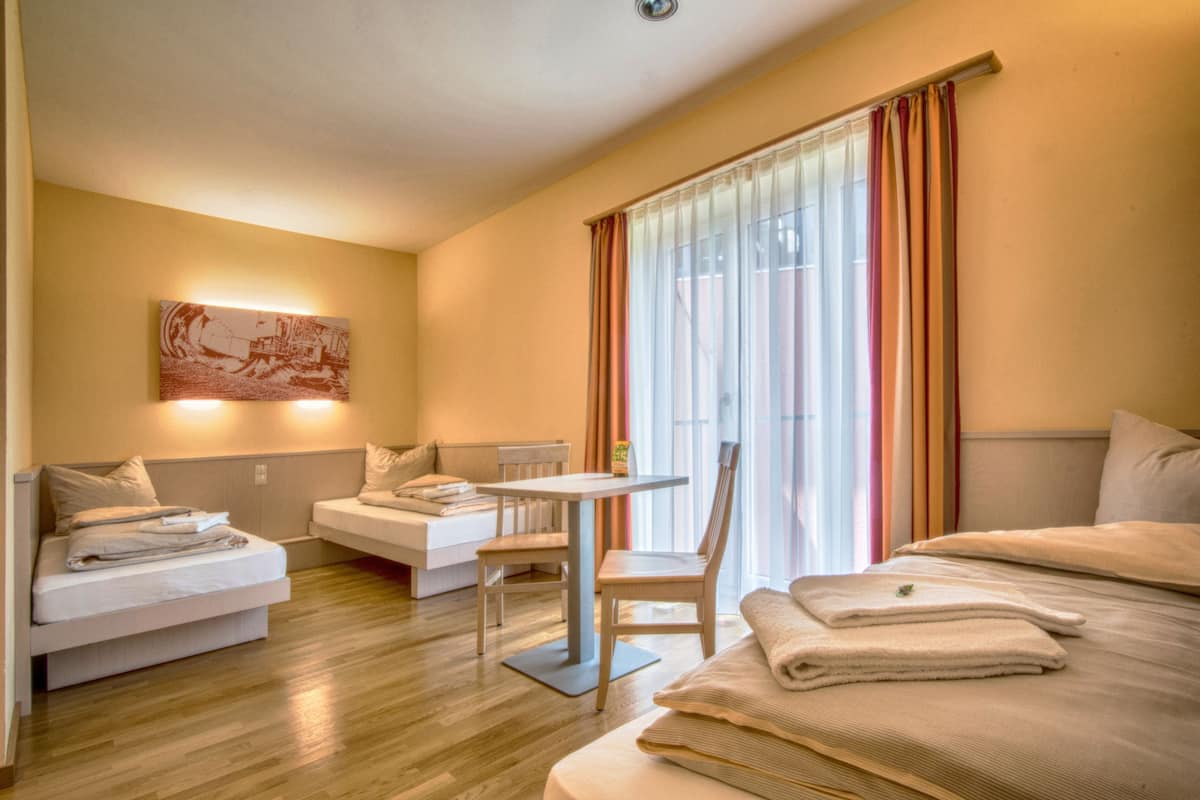 A hotel room with a bed, a sofa, a small table, and a chair.