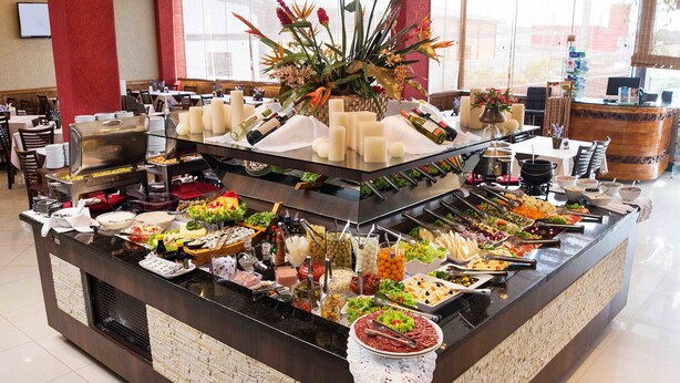 A buffet setup with various food items and a wine selection. - Hotel Estação 101 (Itajai)