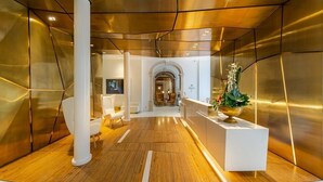 Un vestíbulo moderno con suelo de madera, mobiliario blanco y una recepción con una planta.