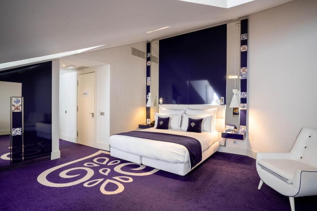 A modern bedroom with a large bed, a white chair, and a unique purple carpet design.