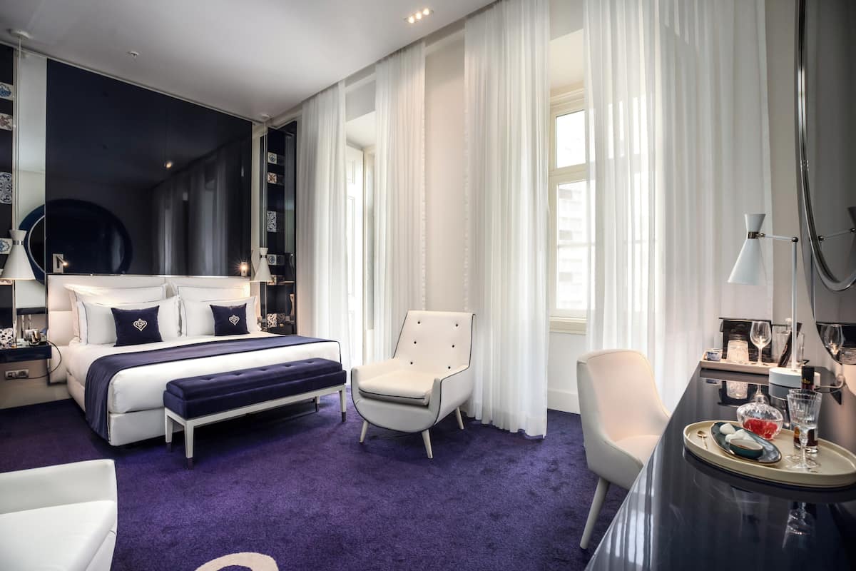 Una habitación de hotel moderna con una cama grande, una zona de estar y una mesa de comedor.
