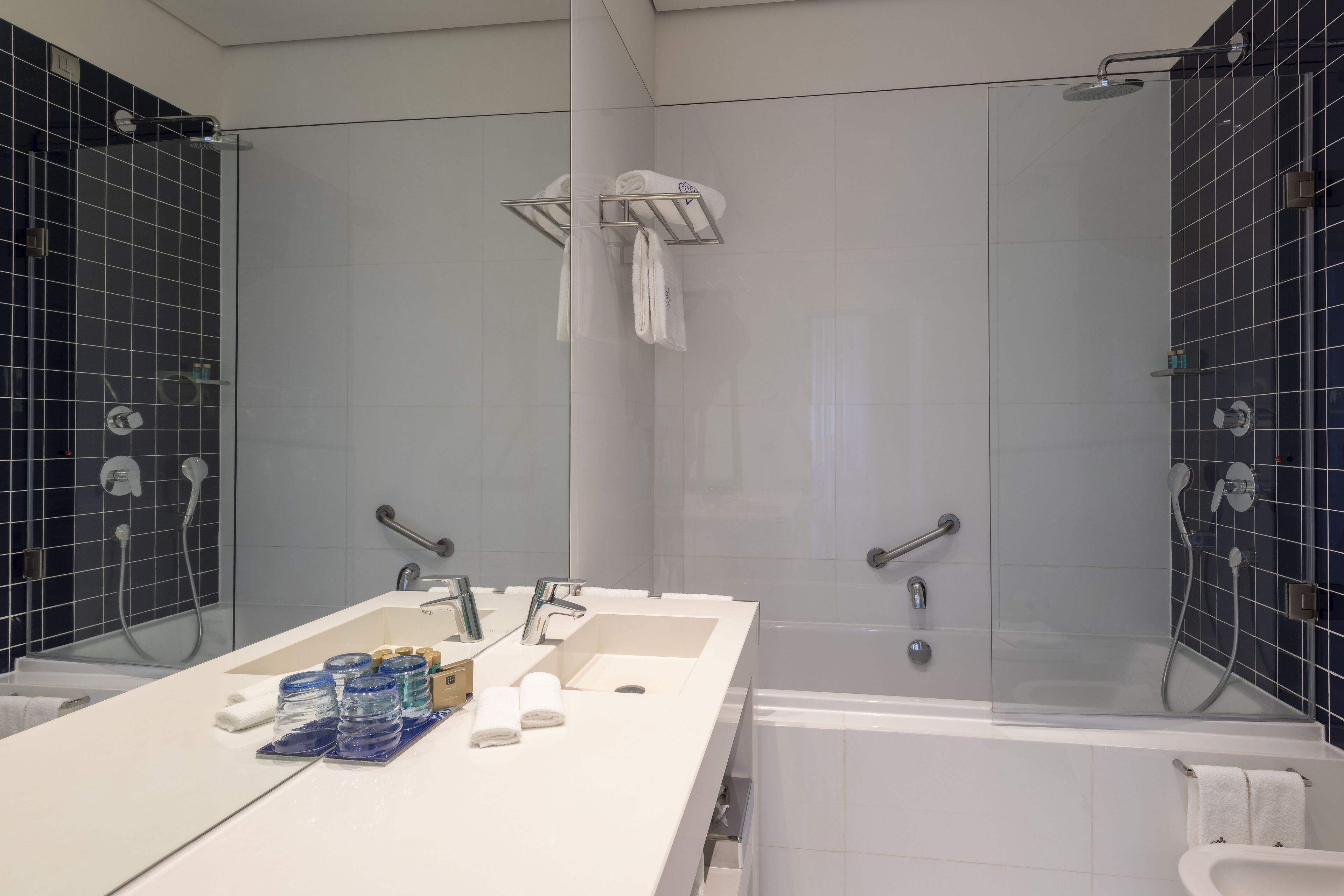 Une salle de bain moderne dotée d’un grand lavabo, de deux miroirs, d’une baignoire et d’un espace douche.
