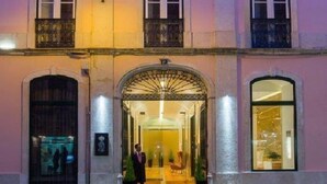 Un edificio rosa con entrada central, ventanas grandes y una lámpara encendida.