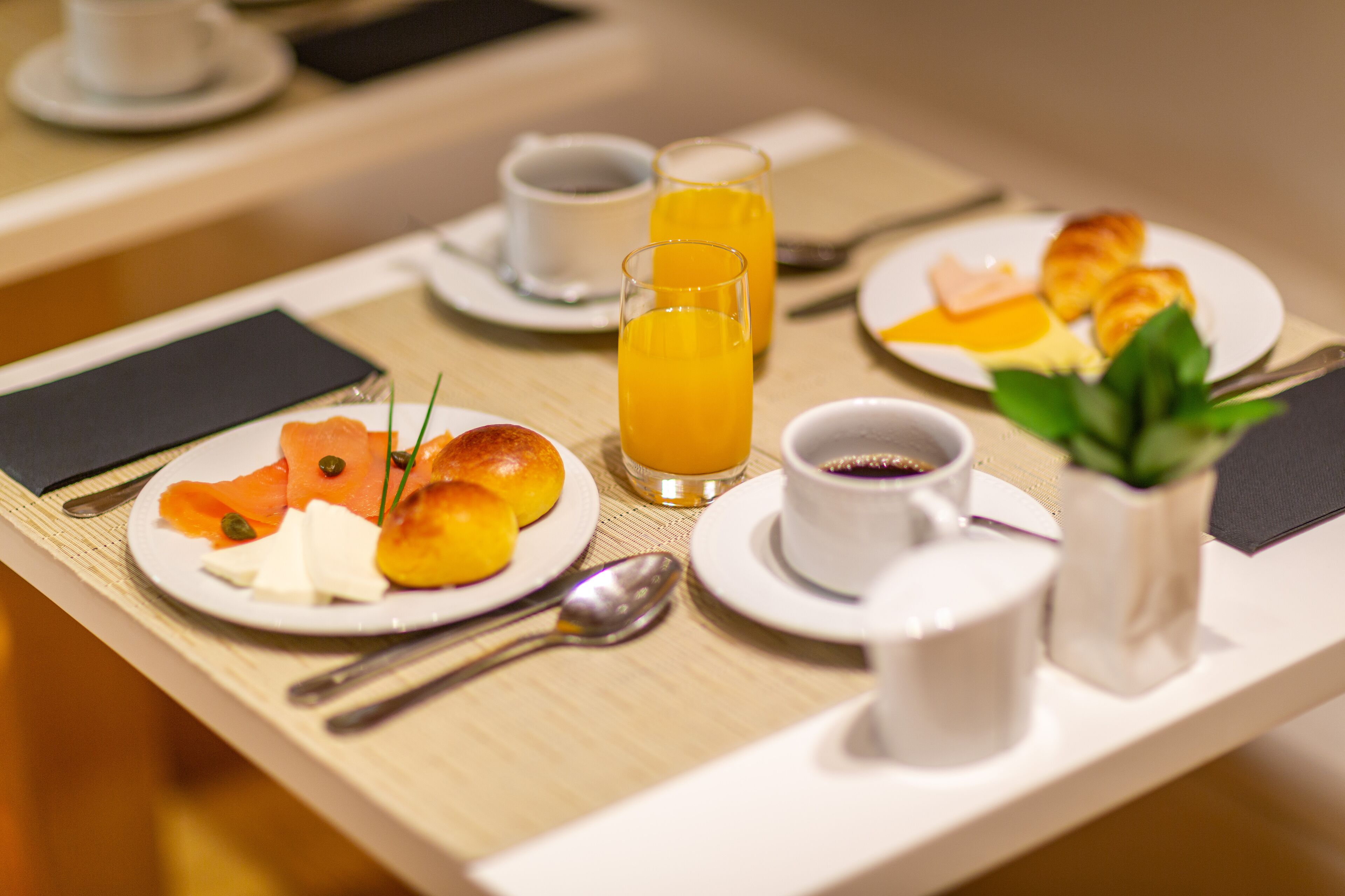 A breakfast setup with plates of food, a glass of orange juice, and a small plant on a table.