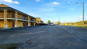 Un motel de dos pisos, con estacionamiento y cielo despejado.
