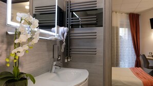 A modern bathroom with a white sink, a mirror, a towel rack, and a potted orchid. - LeNotti Verona (Verona)