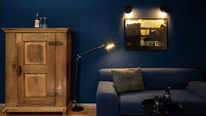 Une pièce avec un meuble en bois, un canapé bleu, une petite table et un tableau accroché au mur.