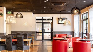 Un restaurante con asientos rojos, un baño visible y una decoración de diseño moderno.