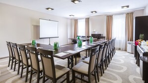 Una sala de conferencias con una mesa larga, sillas, una pantalla de proyector y un espacio para café.