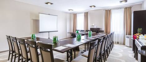 Une salle de conférence équipée d’une longue table, de chaises, d’un écran de projection et d’un coin café.