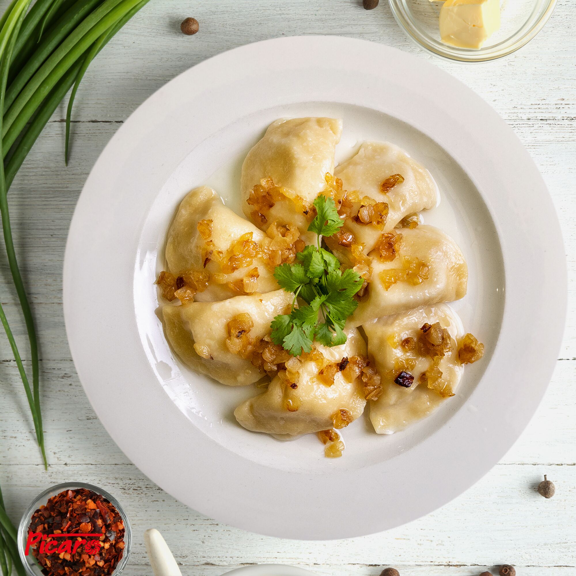 Un piatto di gnocchi guarniti con cipolle e prezzemolo, su un piatto bianco.