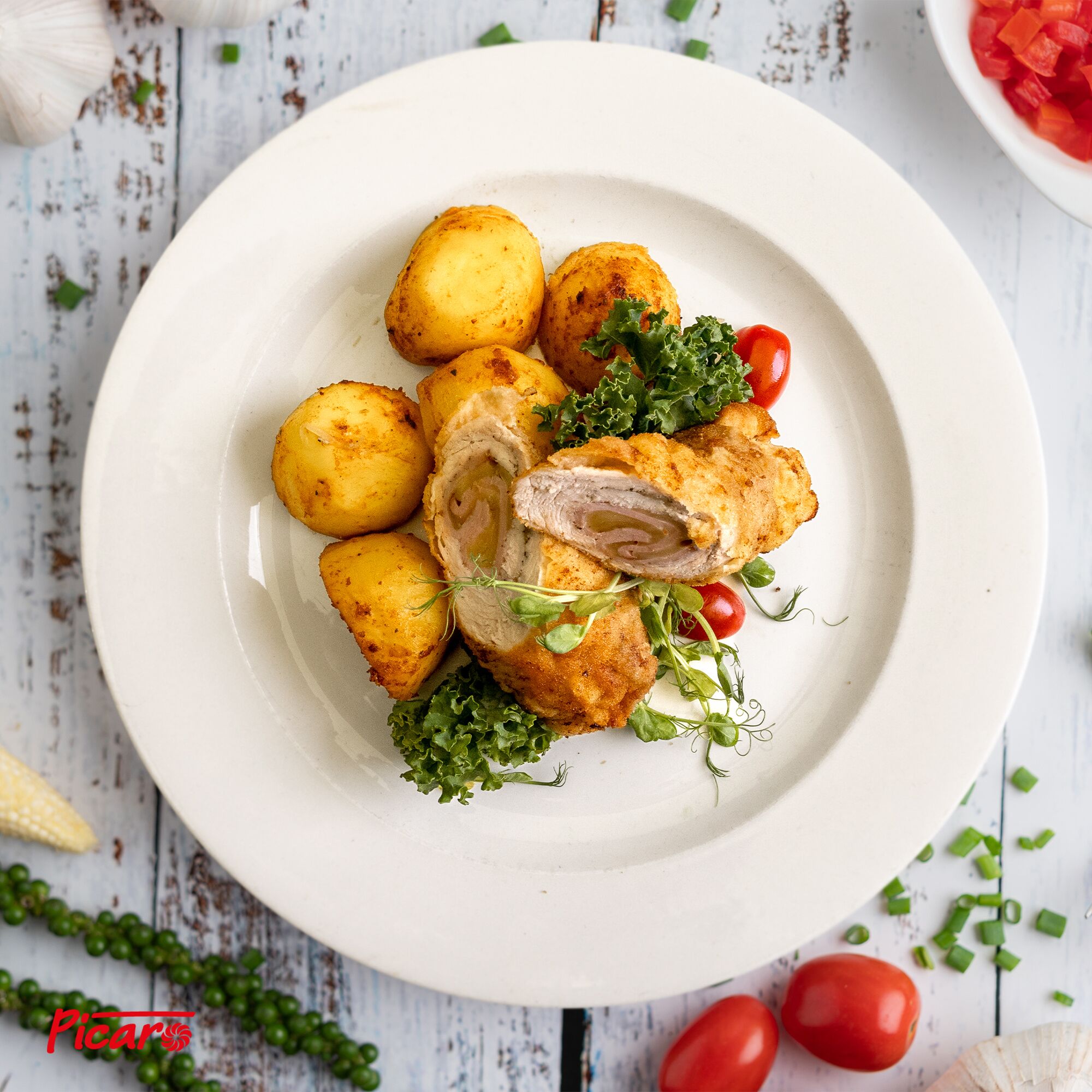 A plate of food with potatoes and a piece of meat, garnished with herbs and cherry tomatoes.