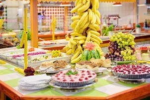 Un bufé con diversas opciones de comida, incluyendo plátanos, uvas, sandía y postres.